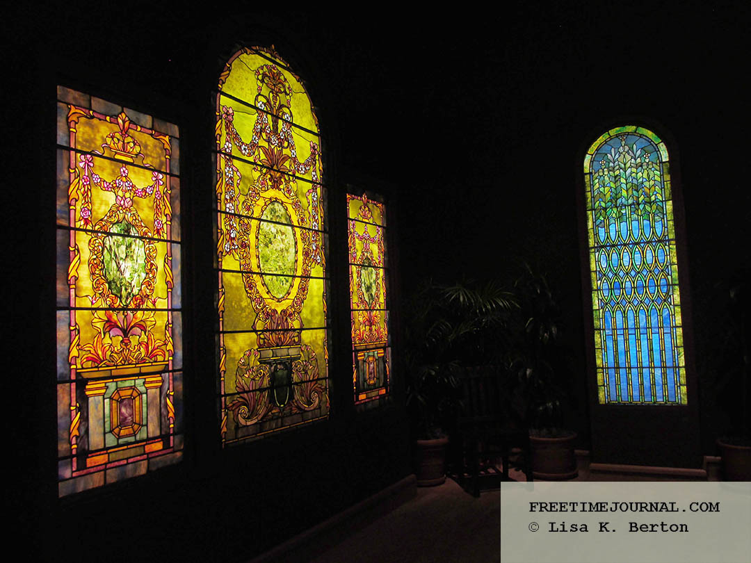 Colorful stained glass windows hung inside a dark room